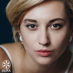 a woman with piercings on her forehead and eyes looking at the camera while posing for a photo