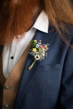 a man in a suit with a boutonniere and flowers on his lapel