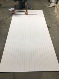 a man is working on a large sheet of white plywood