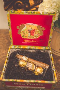 an open box with some chocolates in it on a table next to white flowers