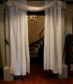 an open door leading to a living room with white drapes hanging from the ceiling