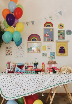 a table with balloons and pictures on the wall behind it in a children's birthday party