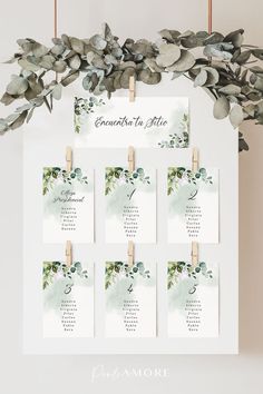 a wedding seating chart with eucalyptus leaves and clothes pins