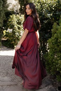 a woman in a red dress is standing outside