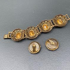 WIDE ~ massive / heavy ~ Vintage ~ Victorian revival ~ gold tone filigree ~ panel bracelet with faceted amber glass cabs ~ Bracelet comes with matching clip-on earrings Unsigned beauty ... Dates mid 20th century Material : gold tone metal amber color glass cabs Measurements : Bracelet is 7 3/4 inches x 1 1/2 inches wide . Earrings are 1 1/4 inches in diameter Condition : Overall all pieces are in good vintage condition with some age related wear ~ can see metal discoloration /darkening ~ Some li Antique Jeweled Metal Jewelry, Jeweled Antique Gold Brass Jewelry, Victorian Jeweled Gold Jewelry, Victorian Style Jeweled Gold Jewelry, Vintage Jeweled Yellow Gold Jewelry, Vintage Yellow Gold Jeweled Jewelry, Vintage Amber Jewelry For Party, Gold Metal Bracelet With Cabochon, Gold Metal Bracelets With Cabochon