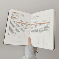 someone is holding an open book with the pages lined up and numbers on it, in front of a gray background