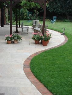 an outdoor patio with potted plants on the side and a bench in the middle