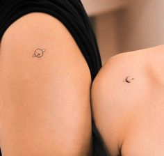 the back of a woman's left shoulder with a small saturn tattoo on it