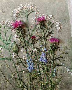 some flowers that are sitting on a piece of cloth with green stems and purple flowers