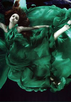 a woman in a green dress floating under water