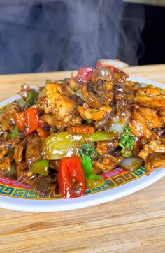 a plate filled with chicken and vegetables on top of a wooden table