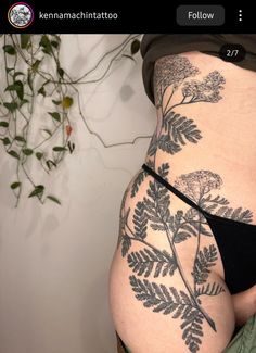 a woman's stomach with tattoos on it and leaves in the bottom part of her body