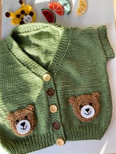 a green sweater with teddy bears on the front and buttons on the back that are attached to it