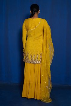 Yellow short kurta with hand embroidery of zardozi with dull gold, copper and antique sequins. Comes with tiered sharara and mukaish work dupatta.
Component: 3
Pattern: Hand Embroidered
Type Of Work: Zardozi, Mukaish, Sequins
Neckline: V-Neck
Sleeve Type: Churidar Sleeves
Fabric: Kurta: Chinon, Georgette, Dupatta: Organza, Lining: Taffeta
Color: Yellow
Other Details: 
Tiered sharara
Leaf shaped neckline
Closure: Kurta: Back zipper
Occasion: Mehendi and Haldi - Aza Fashions Semi-stitched Floor-length Sharara With Dori Work, Diwali Georgette Sharara With Zari Work, Bollywood Style Semi-stitched Sharara With Dori Work, Diwali Zari Work Georgette Sharara, Diwali Sharara With Dabka Work And Traditional Drape, Semi-stitched Sharara With Dori Work In Chinon, Anarkali Sharara With Dori Work In Georgette, Diwali Georgette Sharara With Dori Work, Semi-stitched Sharara With Dori Work And Straight Kurta