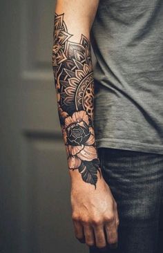 a man with a tattoo on his arm and hand is holding a flower in front of him