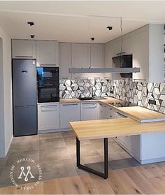 a kitchen with white cabinets and wood flooring, including a wooden table in the center