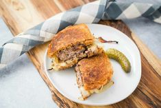 a sandwich cut in half sitting on top of a white plate next to a pickle