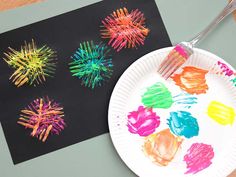 a paper plate with paint on it next to a black piece of paper that has different colored hand prints on it