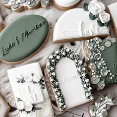 decorated cookies are arranged on a table with white and green decorations, such as flowers