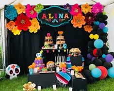 a table topped with cakes and desserts under a tent covered in paper flower decorations