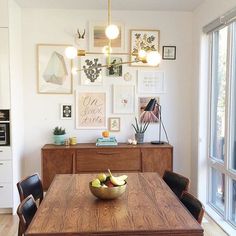 a dining room table with some fruit on it and pictures hanging above the table in front of them