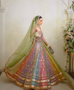 a woman in a colorful wedding dress standing next to a vase with flowers on it