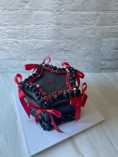 a decorated cake on top of a white paper with red ribbon around the edges and an ornament in the middle