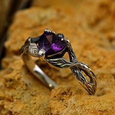 a silver ring with an amethorate stone in the center on a rock