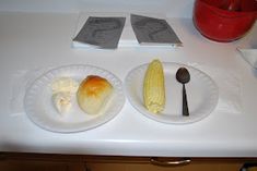 two paper plates with corn on the cob and butter