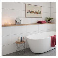 a white bath tub sitting in a bathroom next to a shelf with candles on it