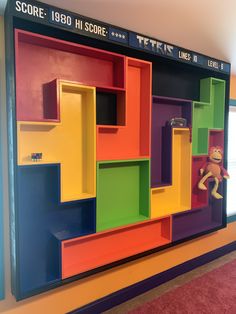 a colorful wall with shelves and stuffed animals on the bottom shelf in front of it