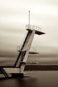 a tall structure with stairs going up to it's sides in the water, against a cloudy sky