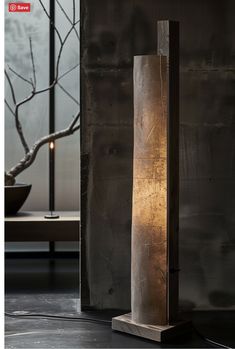 a tall wooden lamp sitting on top of a table next to a vase and tree