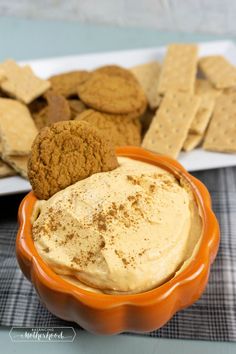 an orange bowl filled with hummus and crackers