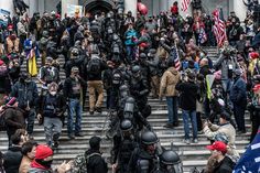 a large group of people standing in front of a building with flags and riot gear