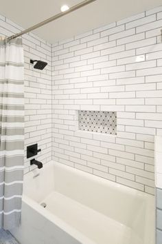 a bathroom with white and gray tile, shower curtain, bathtub and sink in it