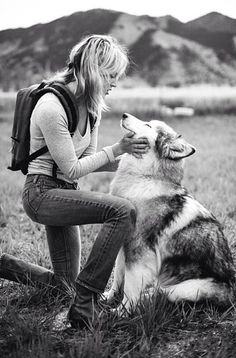 a woman is petting her dog in the grass