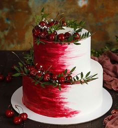 a red and white wedding cake with berries on the top is sitting on a table