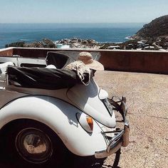 an old car is parked in front of the ocean