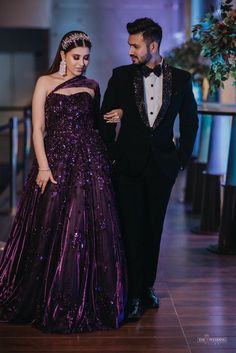 a man in a tuxedo standing next to a woman in a purple dress