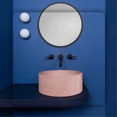 a bathroom with blue walls and a round mirror on the wall next to a sink