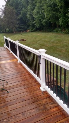 a wooden deck with white railing and black rails