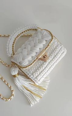 a white purse with gold hardware and tassels