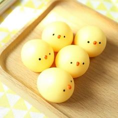 four yellow plastic eggs sitting on top of a wooden tray next to chopsticks