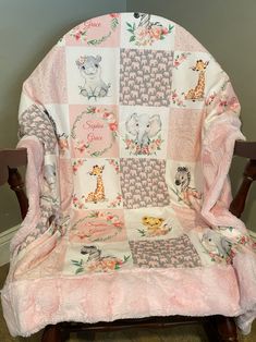 a pink and white baby blanket on top of a wooden chair with an animal theme