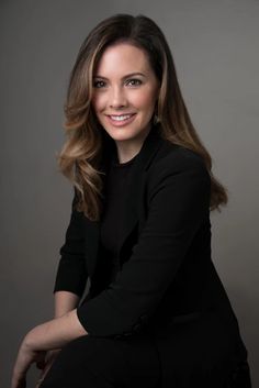 a woman in black shirt and pants posing for a photo with her hands on her knees