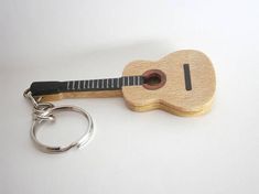 a wooden guitar shaped keychain with a black strap