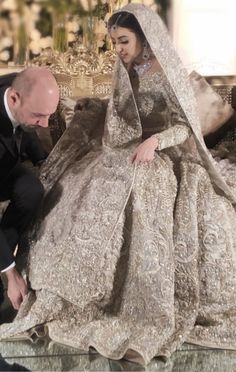 a man kneeling down next to a woman in a wedding dress