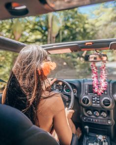 a woman sitting in the driver's seat of a car with an orange flower on it