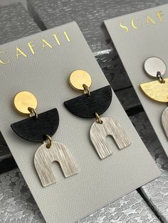 "These earrings have a stylish geometric minimalist look with push back stud posts. The glossy gold is 18 K gold over brass. They are glossy because they're rack plated. This means that the pieces are hand hung so they receive the optimal amount of coverage. The black is oxidized metal. The silver is a matte silver alloy over brass which is a white silver. The white silver goes well with shiny gold and black. The different finishes enhance each other to make an interesting mix of metals. We offe Modern Dangle Plug Earrings, Modern Geometric Earrings, Modern Geometric Earrings For Pierced Ears, Minimalist Earrings Gold, Mixed Metal Earrings, Earrings Geometric, Half Circle, Earrings Minimalist, Metal Earrings